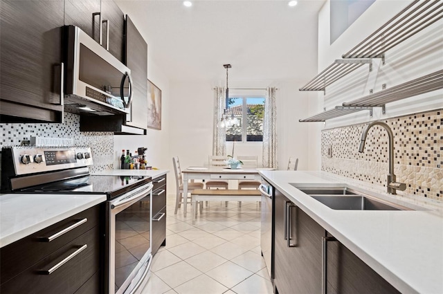 kitchen featuring sink, light tile patterned floors, tasteful backsplash, decorative light fixtures, and stainless steel appliances