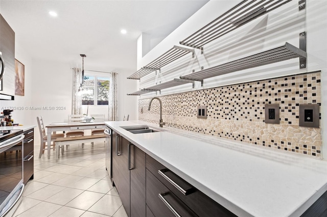 kitchen featuring appliances with stainless steel finishes, backsplash, sink, light tile patterned floors, and decorative light fixtures