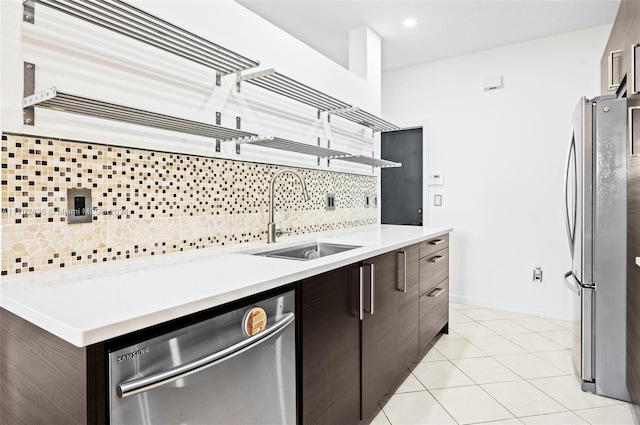 kitchen with sink, backsplash, dark brown cabinets, light tile patterned floors, and appliances with stainless steel finishes