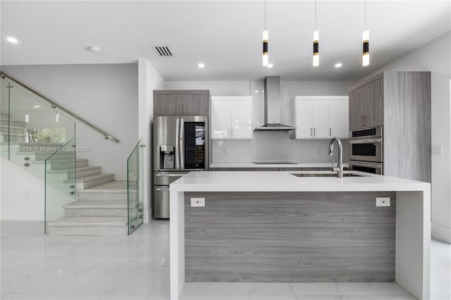 kitchen featuring decorative light fixtures, sink, white cabinets, stainless steel appliances, and wall chimney range hood