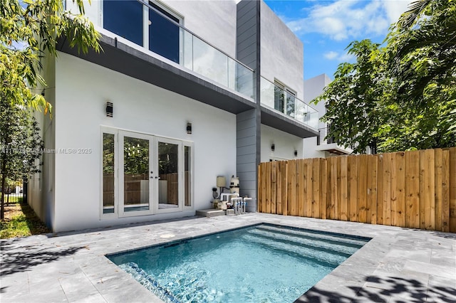 rear view of house featuring a fenced in pool, a patio, and french doors