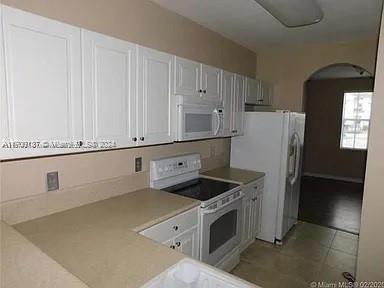 kitchen with white cabinetry, white appliances, and light tile patterned floors