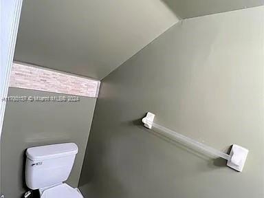 bathroom featuring toilet and lofted ceiling