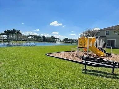 view of jungle gym featuring a lawn and a water view