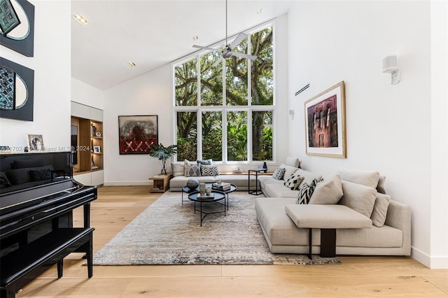 living room with high vaulted ceiling, ceiling fan, light wood-type flooring, and a wealth of natural light