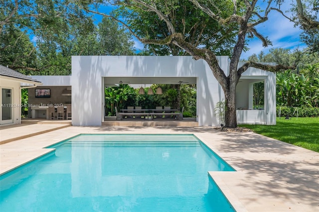 view of swimming pool with ceiling fan, a patio area, and an outdoor kitchen