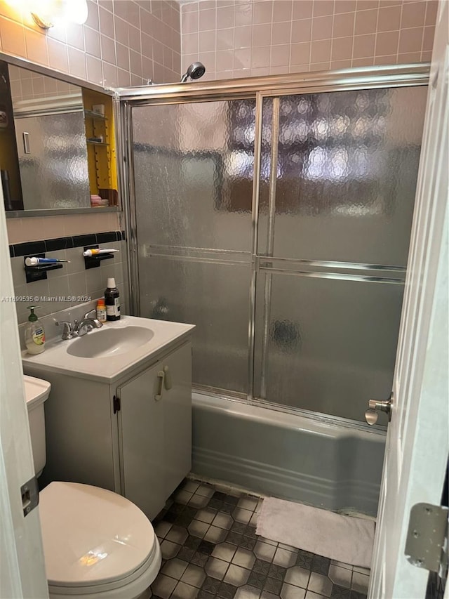 full bathroom featuring tile patterned flooring, backsplash, bath / shower combo with glass door, vanity, and tile walls