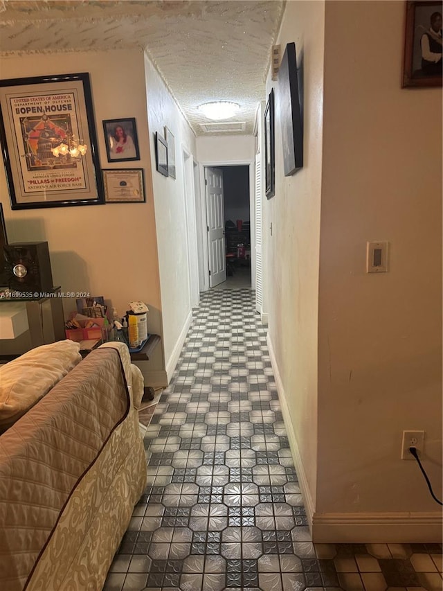 corridor featuring dark tile patterned floors and a textured ceiling