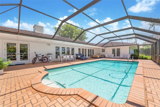 view of pool featuring glass enclosure, a patio area, french doors, and grilling area