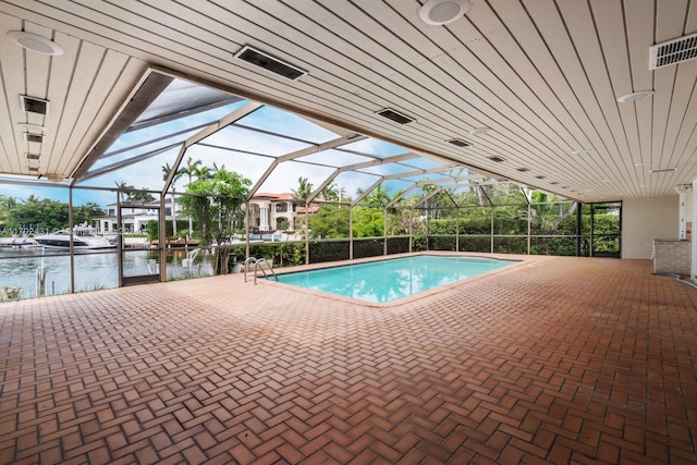 view of swimming pool featuring glass enclosure, a patio area, and a water view