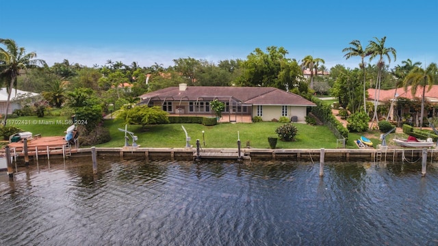 rear view of house with a water view, a lanai, and a lawn