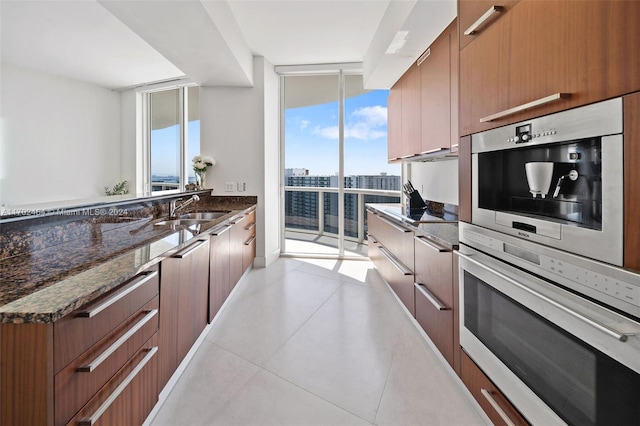 kitchen with dark stone countertops, sink, a healthy amount of sunlight, and stainless steel oven