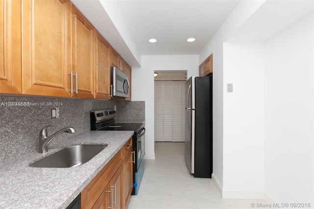 kitchen with light stone countertops, appliances with stainless steel finishes, tasteful backsplash, and sink