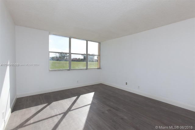 empty room featuring a textured ceiling and dark hardwood / wood-style floors