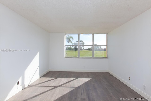 spare room featuring a textured ceiling and dark wood-type flooring