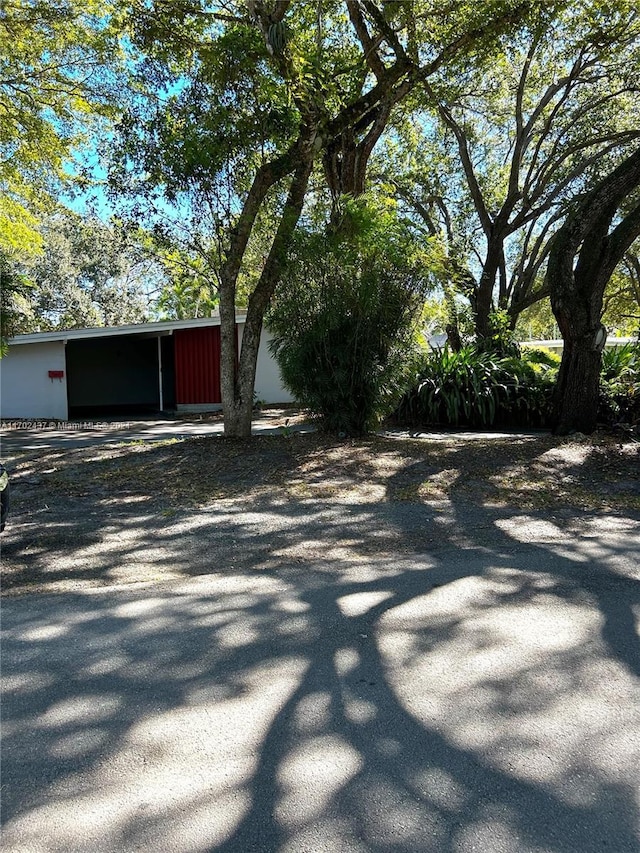 12725 SW 80th Ave, Pinecrest, FL 33156 - view of home's exterior featuring a carport, driveway, a pole building, and an outbuilding