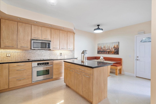 kitchen with decorative backsplash, appliances with stainless steel finishes, a center island, and light tile patterned floors