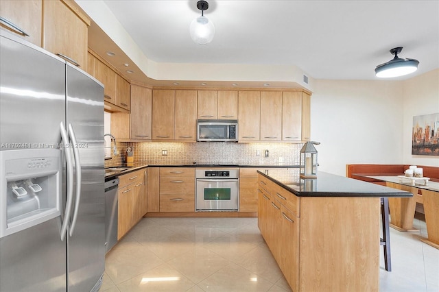 kitchen with appliances with stainless steel finishes, backsplash, sink, light brown cabinets, and a center island