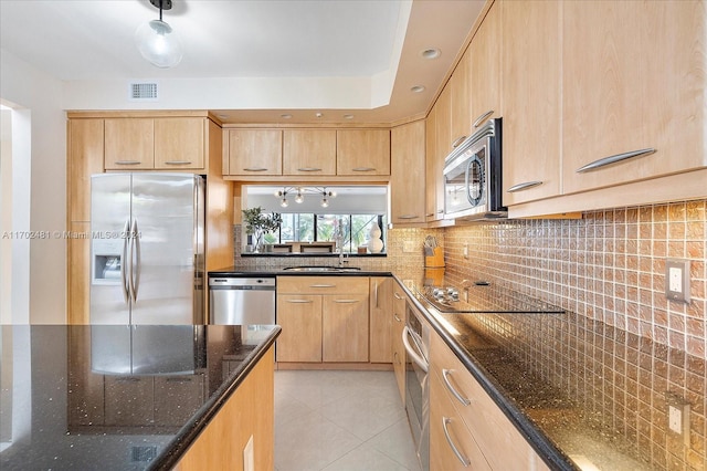 kitchen featuring light brown cabinets, dark stone counters, sink, light tile patterned floors, and appliances with stainless steel finishes