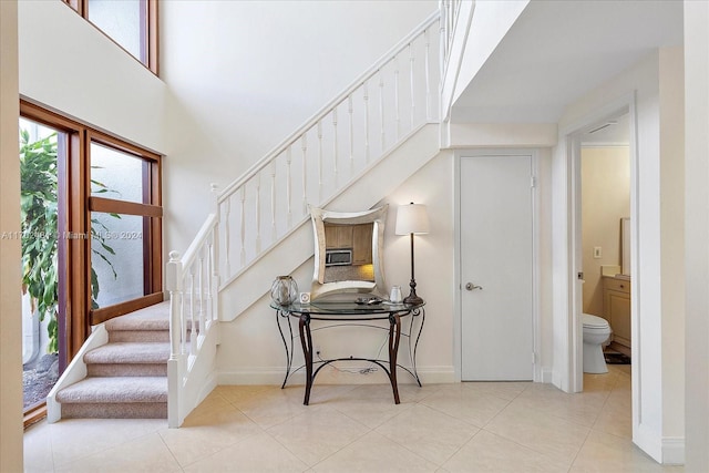 stairway with tile patterned floors and a high ceiling