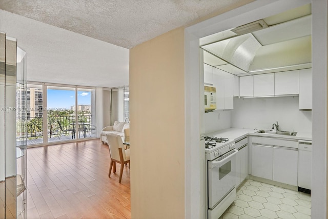 kitchen featuring white cabinets, light wood-type flooring, white appliances, and floor to ceiling windows