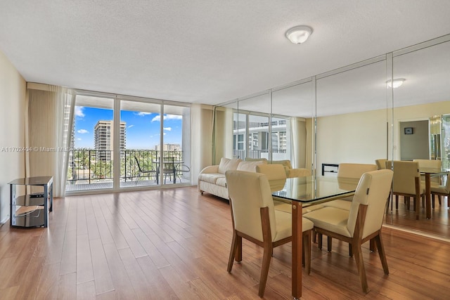 dining room featuring floor to ceiling windows, wood-type flooring, and a textured ceiling