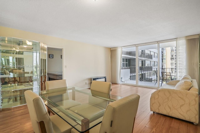 dining area with a textured ceiling, light wood-type flooring, and a wall of windows