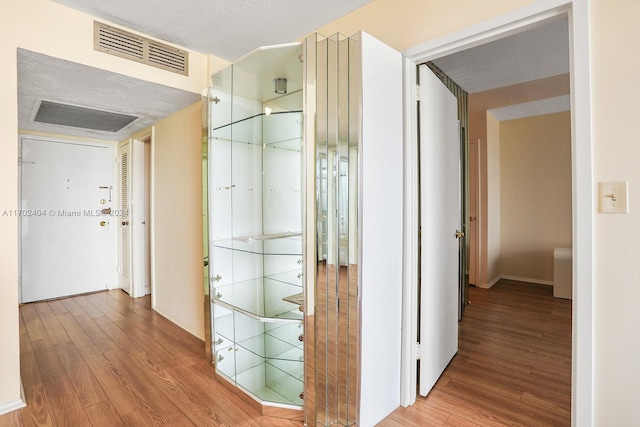 corridor with hardwood / wood-style floors and a textured ceiling