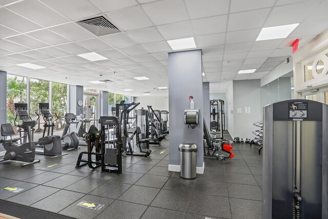 gym featuring floor to ceiling windows and a drop ceiling