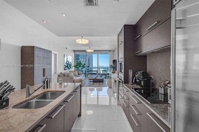 kitchen with tasteful backsplash, light stone counters, stainless steel appliances, sink, and light tile patterned floors