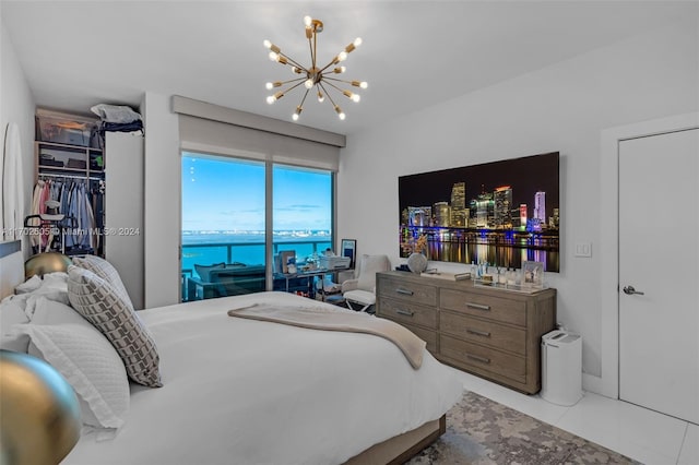 bedroom featuring access to outside, light tile patterned floors, and an inviting chandelier