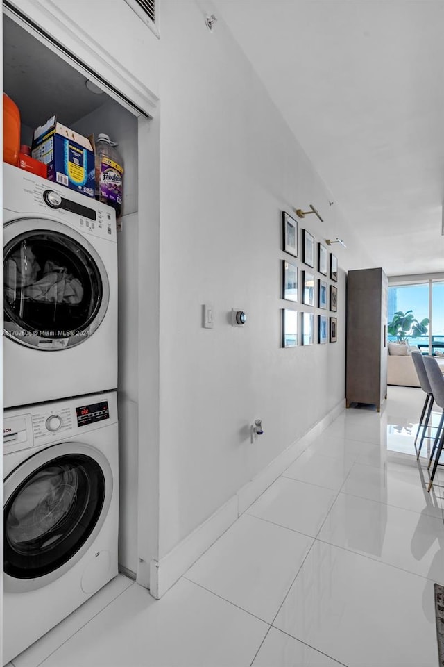 laundry area featuring light tile patterned floors and stacked washer / dryer