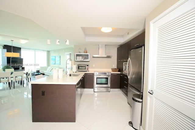 kitchen with appliances with stainless steel finishes, dark brown cabinetry, wall chimney range hood, pendant lighting, and light tile patterned flooring