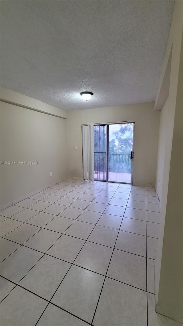 unfurnished room with light tile patterned flooring and a textured ceiling