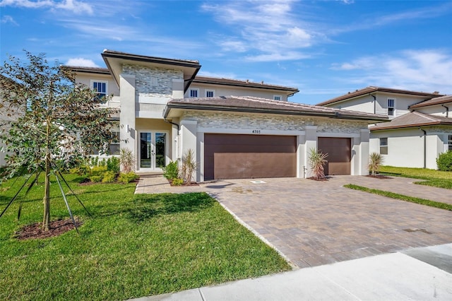 prairie-style home featuring french doors, a front lawn, and a garage