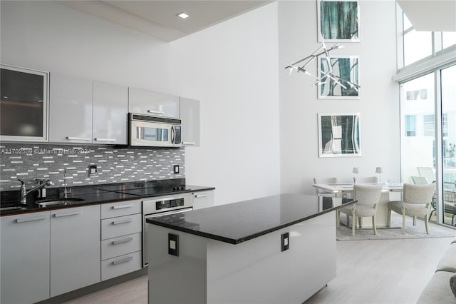 kitchen featuring tasteful backsplash, white cabinets, appliances with stainless steel finishes, a kitchen island, and light wood-type flooring