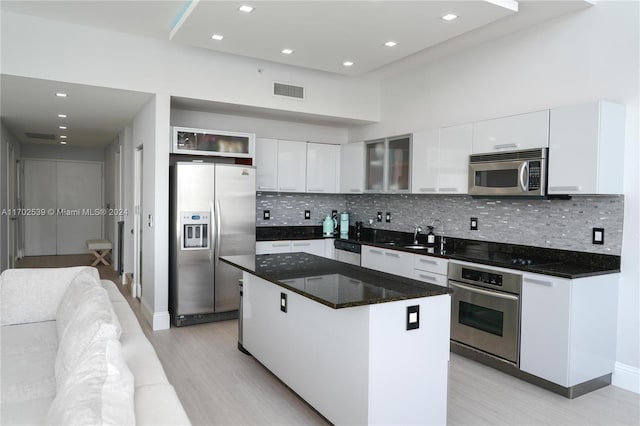 kitchen with backsplash, white cabinetry, a kitchen island, and stainless steel appliances