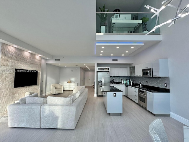 kitchen featuring a center island, stainless steel appliances, light hardwood / wood-style flooring, decorative backsplash, and white cabinets