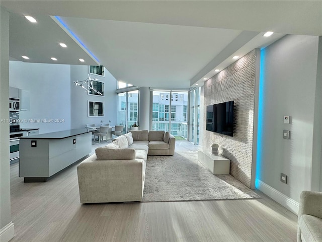 living room featuring expansive windows, light hardwood / wood-style floors, and an inviting chandelier