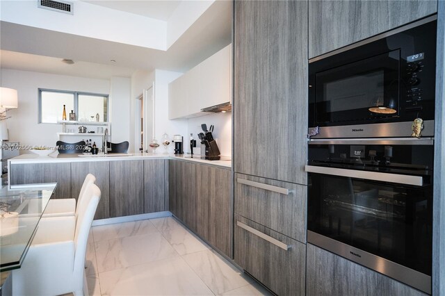 kitchen with built in microwave, stainless steel oven, sink, black electric stovetop, and dark brown cabinets