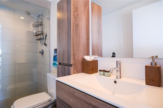 bathroom with vanity, toilet, and a tile shower