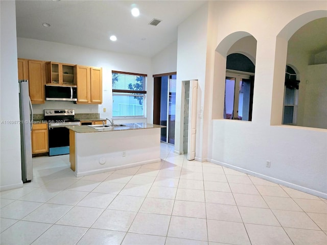 kitchen featuring appliances with stainless steel finishes, a breakfast bar, vaulted ceiling, light tile patterned floors, and an island with sink