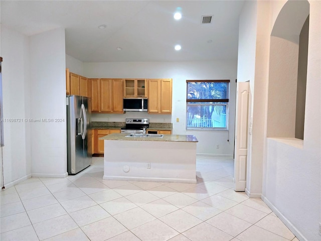 kitchen featuring a center island with sink, sink, light tile patterned floors, appliances with stainless steel finishes, and light stone counters