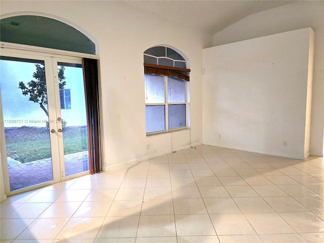 spare room with french doors, a wealth of natural light, and light tile patterned flooring