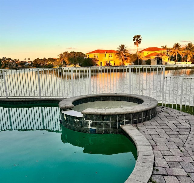 surrounding community featuring a swimming pool with hot tub and a water view