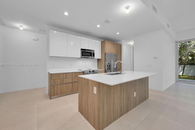 kitchen with sink, stainless steel appliances, white cabinets, an island with sink, and light tile patterned flooring