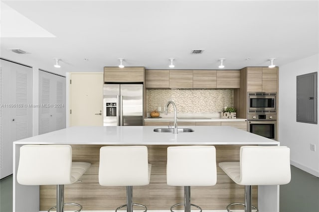 kitchen with a kitchen bar, an island with sink, and stainless steel appliances