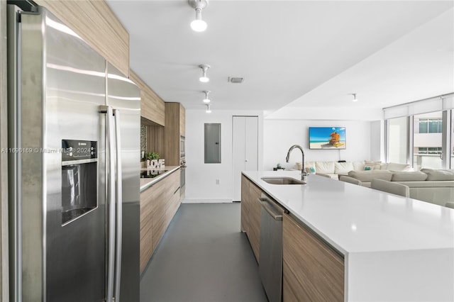 kitchen with a kitchen island with sink, sink, and appliances with stainless steel finishes