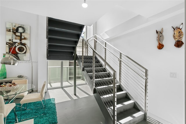 stairs with concrete flooring and a wall of windows