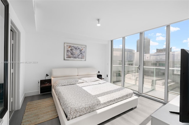 bedroom featuring hardwood / wood-style floors, floor to ceiling windows, and access to exterior